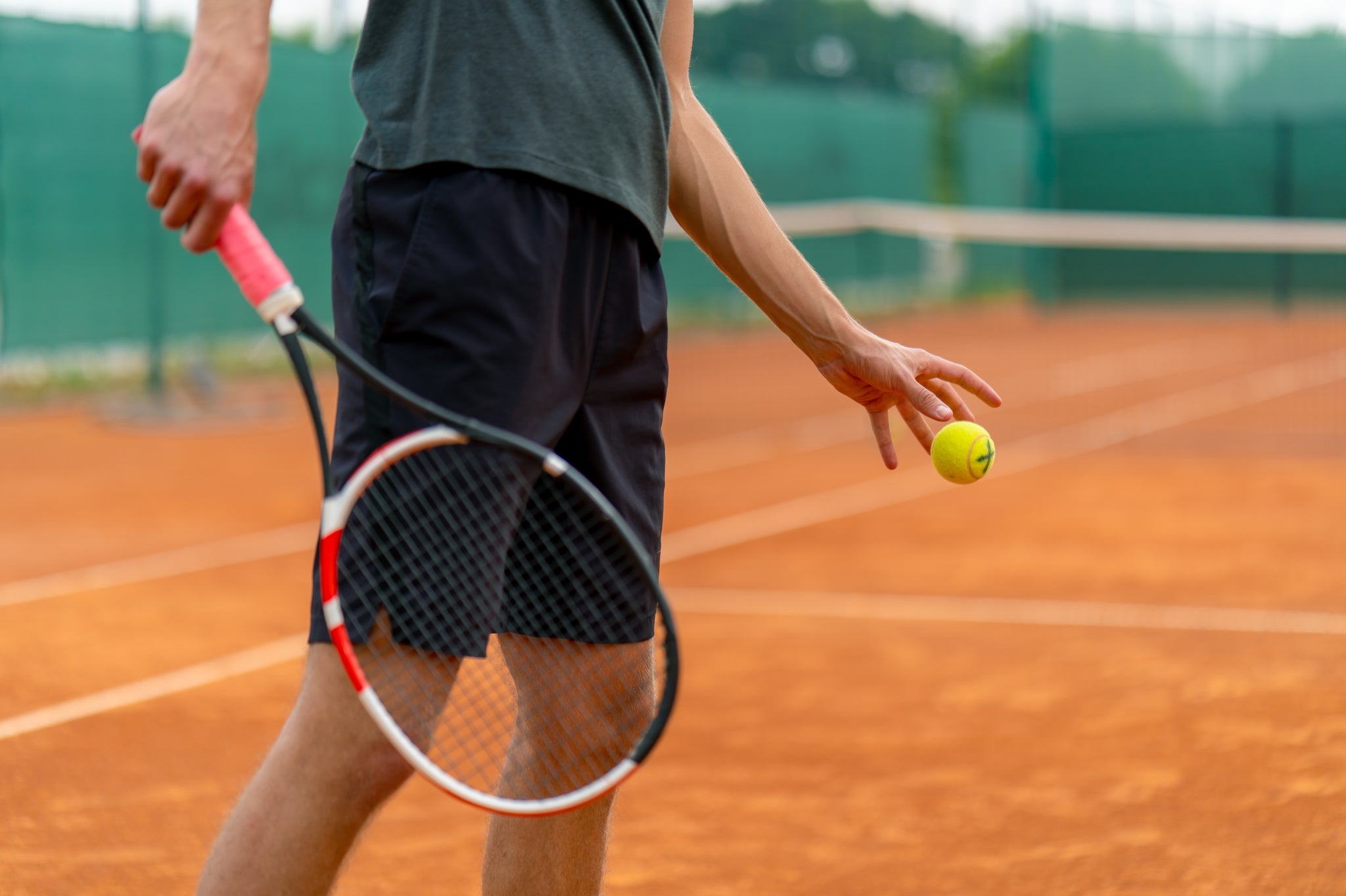 Man with tennis racket in hand getting ready to serve.