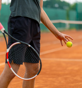 Man with tennis racket in hand getting ready to serve.