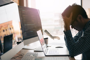 Man at computer with hands holding head
