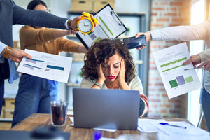 Woman at computer holding her head looking stressed.