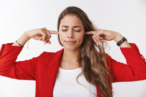 woman with her fingers in her ears and eyes closed