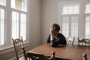 Man sitting at table holding his head