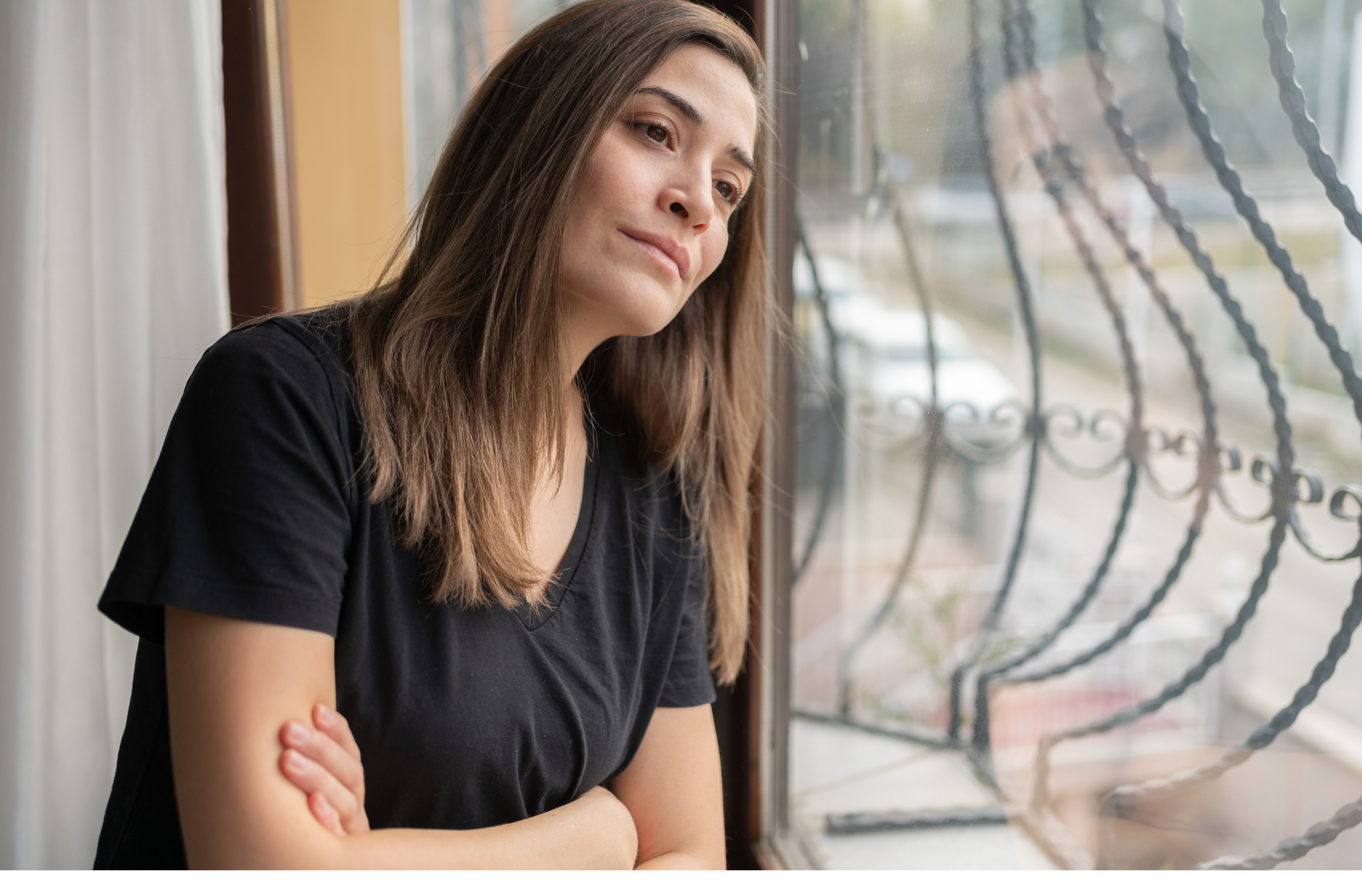 upset woman looking through a barred window.