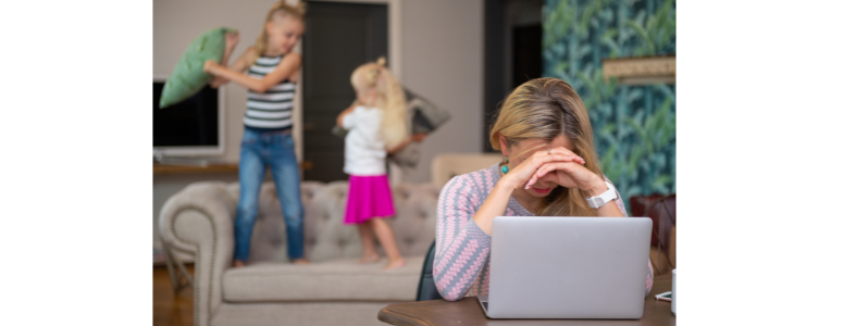 Mom working on laptop, children fighting in background